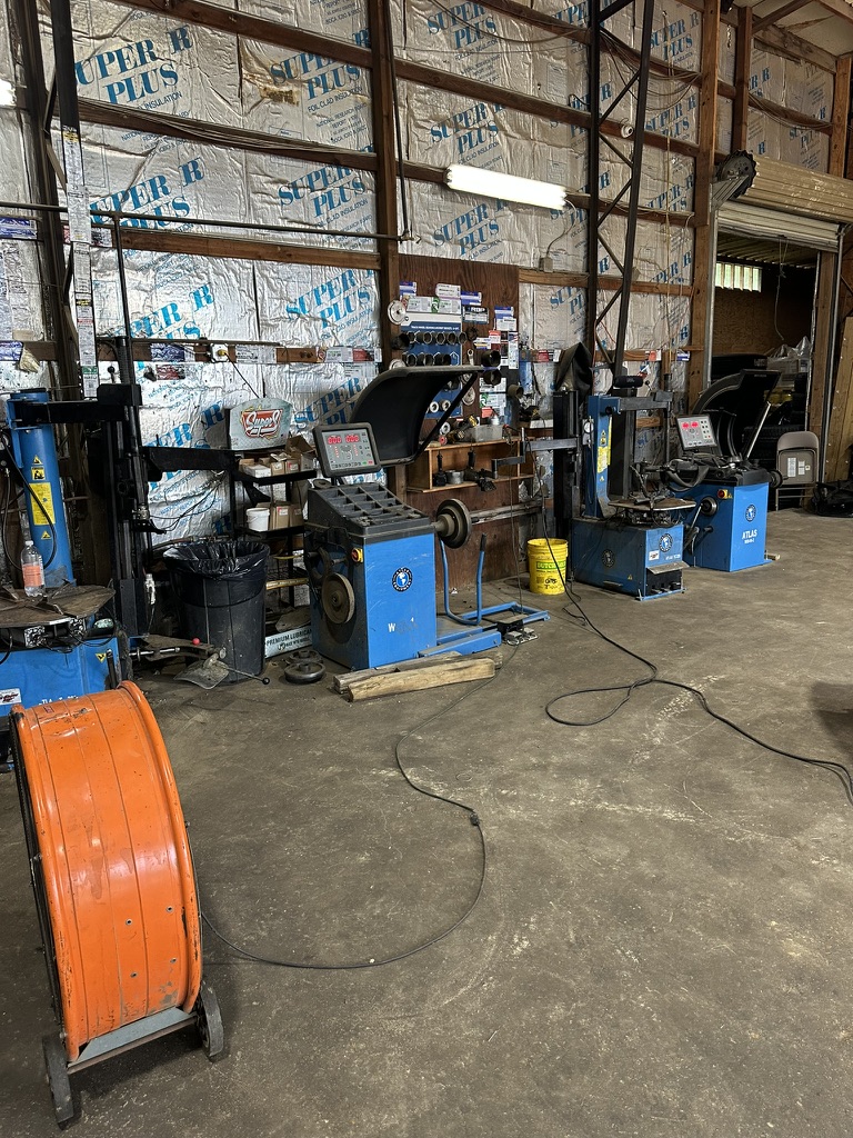 Blue tire changer and wheel balancer machines lined up in a Hazlehurst Tire Company service bay