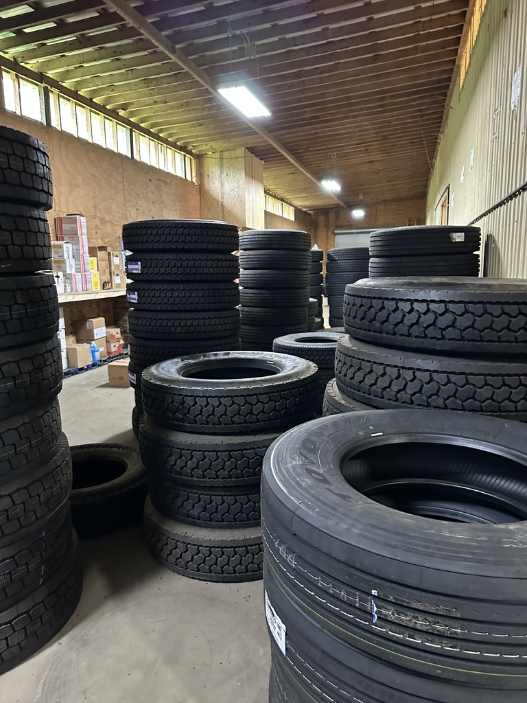 Warehouse aisle stacked with large commercial truck tires at Hazlehurst Tire Company