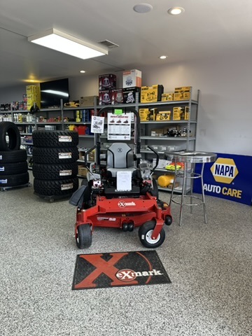 Red Exmark zero-turn mower on the showroom floor beside a NAPA Auto Care sign at Hazlehurst Tire Company
