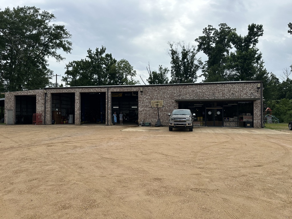Hazlehurst Tire Company brick storefront with open service bays and a pickup truck parked out front